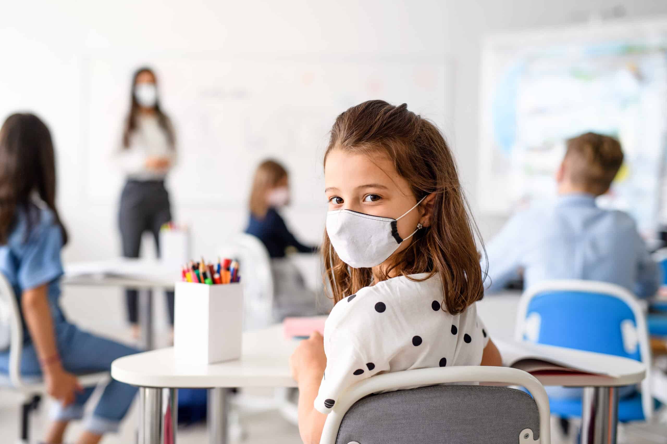 Child with face mask back at school after covid-19 quarantine and lockdown