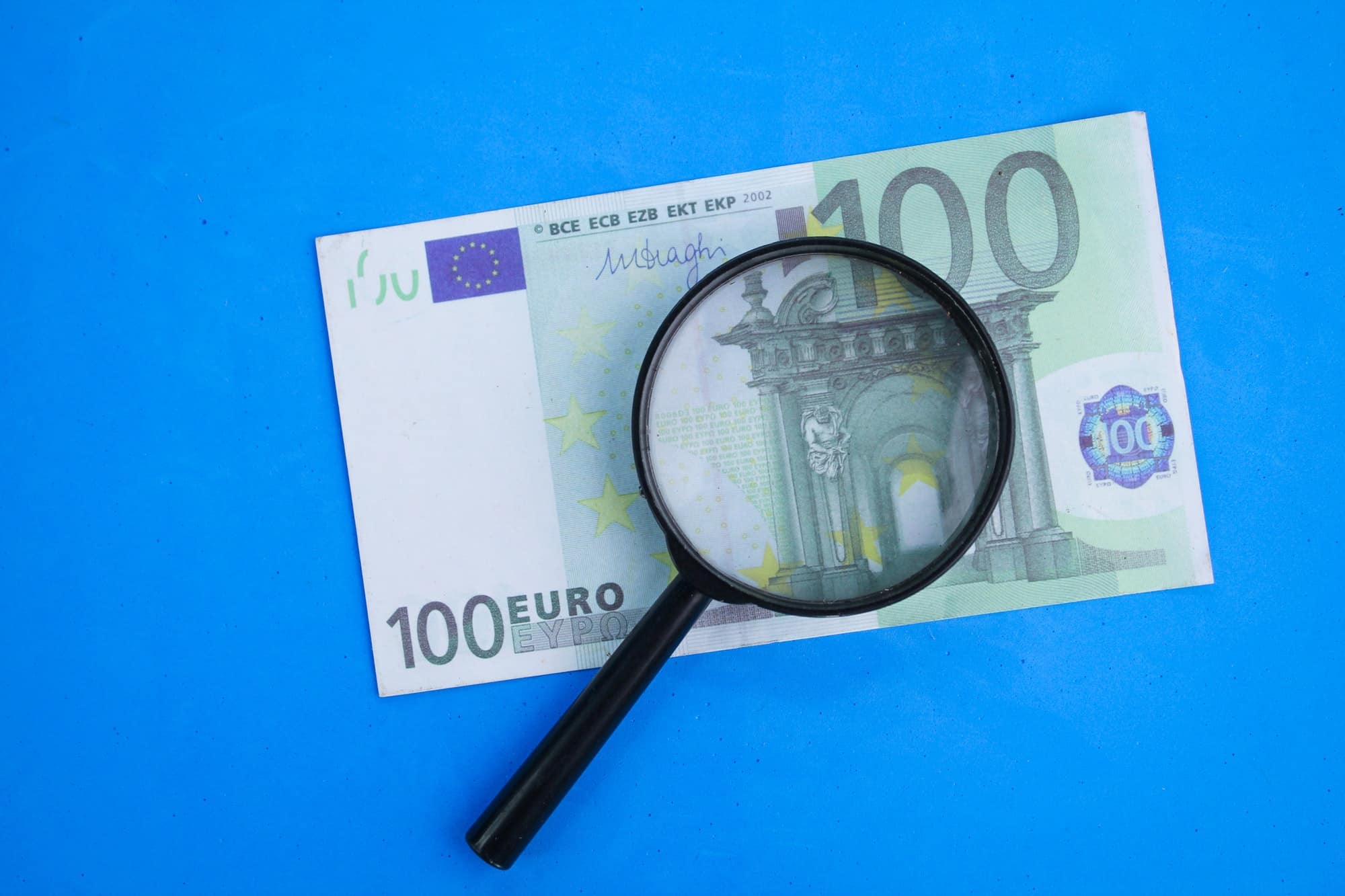 magnifying glass with 100 euros. the concept of investing in euros.