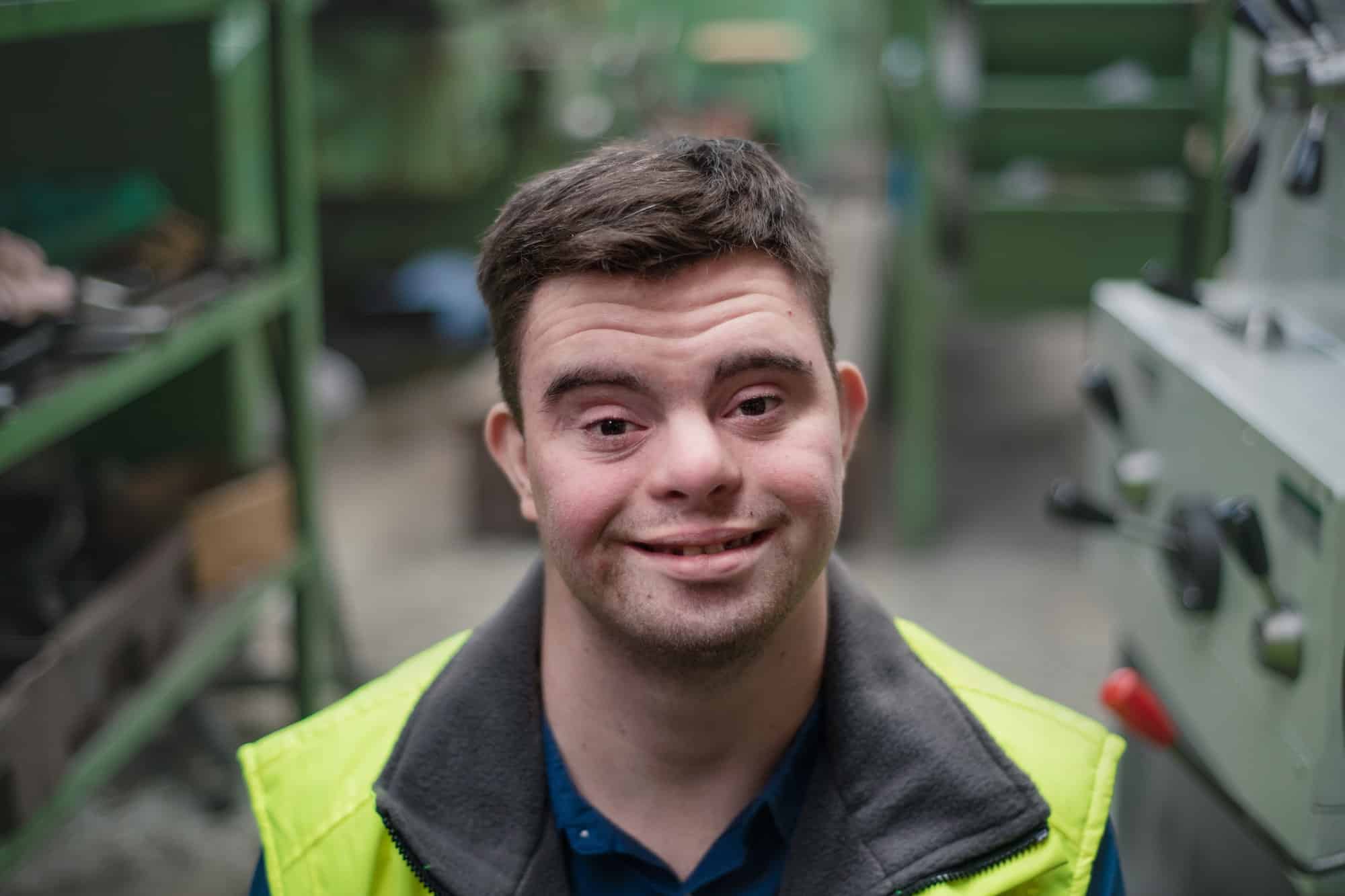 Young man with Down syndrome working in industrial factory, social integration concept.